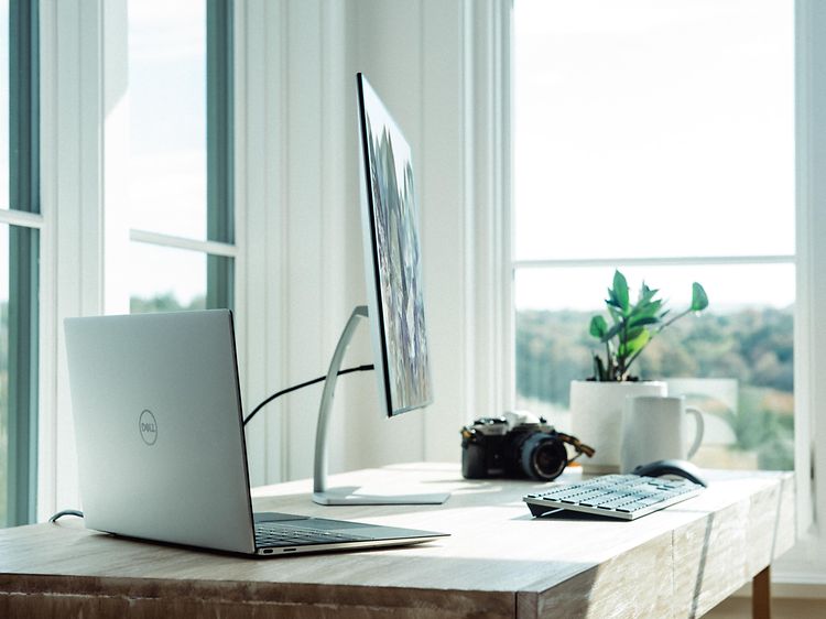 Bærbar computer tilsluttet til en skærm og tastatur på et skrivebord.