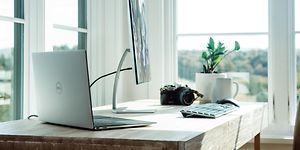 Bærbar computer tilsluttet til en skærm og tastatur på et skrivebord.