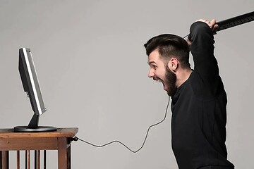 mand bliver sur på sin computer og slår mod skærmen med tastaturet