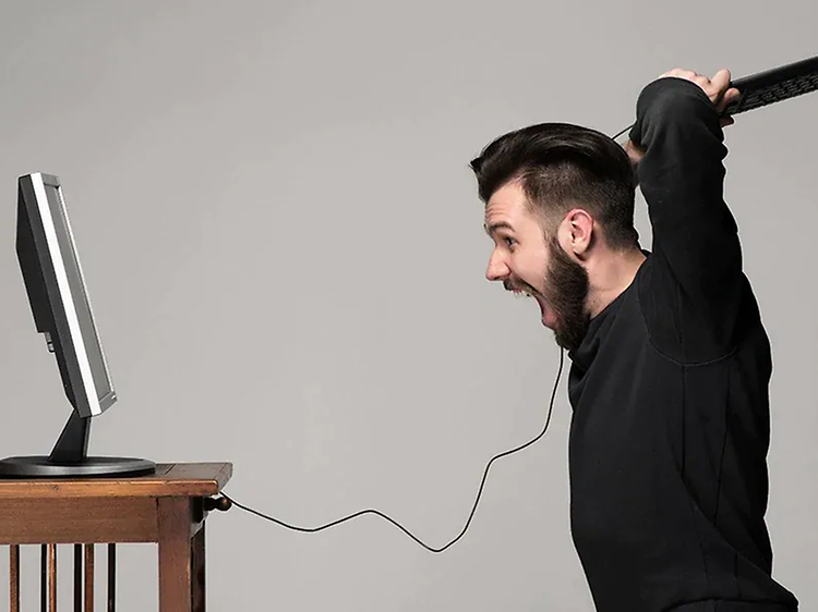 mand bliver sur på sin computer og slår mod skærmen med tastaturet