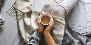 Woman sitting with cup of coffee in bed