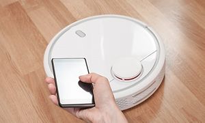 Hvid robotstøvsuger på et trægulv