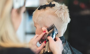 kvindelig frisør der klipper en dreng kort i siderne