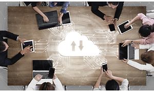 Syv personer omkring et bord arbejder sammen via cloud-lagring