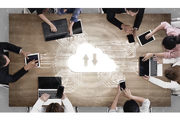Syv personer omkring et bord arbejder sammen via cloud-lagring