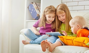 Tre børn der sammen kigger på en tablet