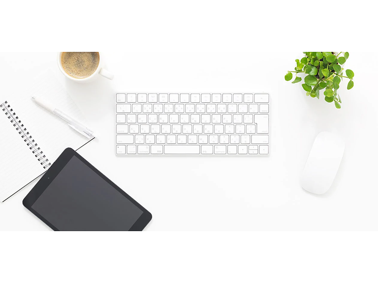 Tablet med et separat tastatur, mus, notesbog, kaffekrus og plante