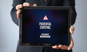 En person holder en tablet med ordene parental control