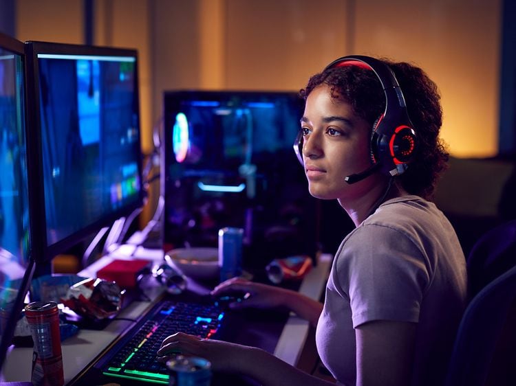 Pge med gaming-headset, der sidder foran hendes gaming-skrivebord