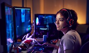 Pge med gaming-headset, der sidder foran hendes gaming-skrivebord