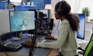 Pige sidder foran hendes gaming desktop og streamer