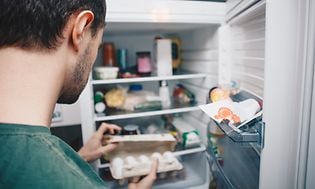 Mand ser på en æggebakke i køleskabet