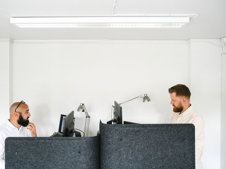 To mænd på et kontor, der arbejder på hver deres computer
