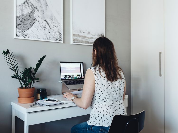 Kvinde, der sidder ved sit hjemmekontor, og arbejder på sin bærbare computer