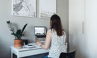 Kvinde, der sidder ved sit hjemmekontor, og arbejder på sin bærbare computer