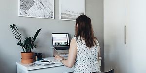 Kvinde, der sidder ved sit hjemmekontor, og arbejder på sin bærbare computer