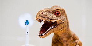 El-tandbørste der står ved siden af en legetøjs dinosaurs