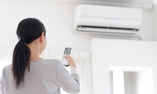 Kvinde der tænder for en varmepumpe/airconditioner
