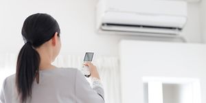 Kvinde der tænder for en varmepumpe/airconditioner