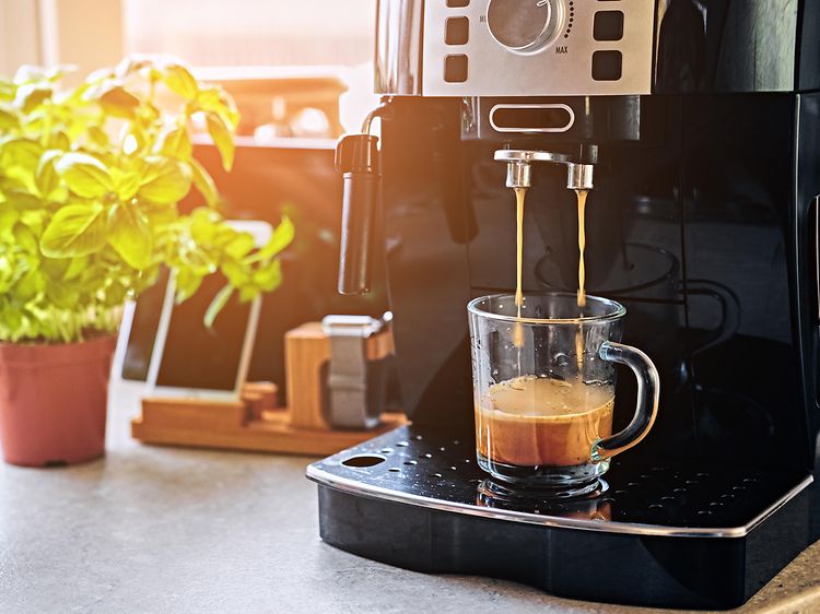 Kaffemaskine der står på et køkkenbord. Kaffemaskinen er igang med at lave en kop kaffe.