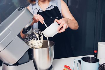 Kvinde der bager en kage i en køkkenmaskine
