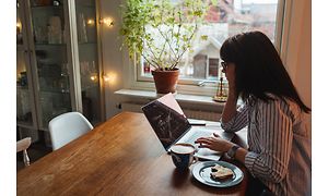 Kvinde sidder ved bord og arbejder hjemmefra