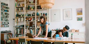 Kvinde, der arbejder på sin bærbare computer ved siden af en mand med et barn på skødet