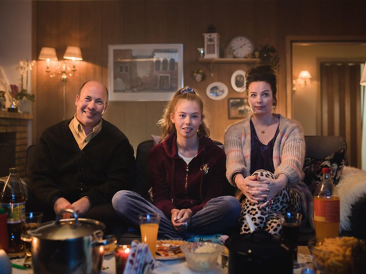 Familie på tre, der sidder på en sofa