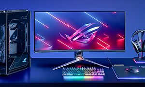 En stationær gamingcomputer med skærm, tastatur, hovedtelefoner og mus på et bord