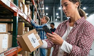 Kvinde, der scanner en pakke med sin telefon