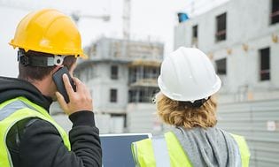 Smartphone og tablet i hænderne på to personer på en byggeplads