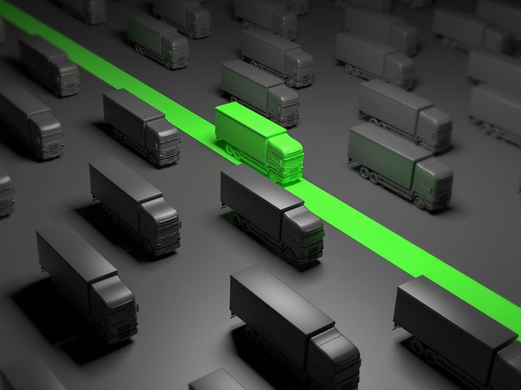 En illustration af en grøn lastbil, der kører mellem sorte lastbiler
