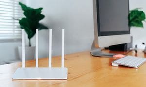 Moderne Wi-Fi-router på et lyst bord på hjemmekontoret