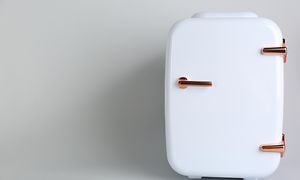 Lille hvidt køleskab på lys grå baggrund