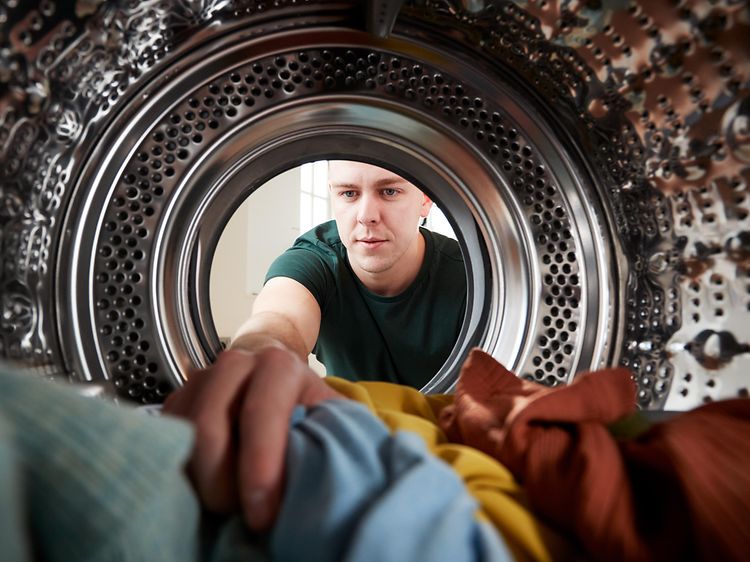 Mand, der fylder tøj i en vaskemaskine
