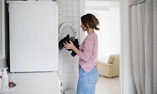 En kvinde, der fylder sin vaskemaskine med vasketøj