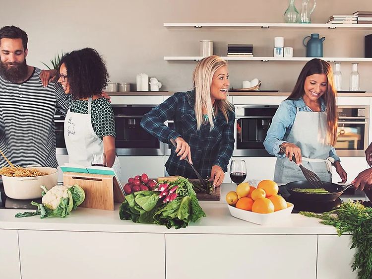 Seks mennesker, der laver mad sammen i et stort køkken