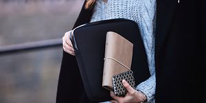 Kvinde, der bærer bærbar computer i et sleeve sammen med sin pung og telefon