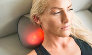 En kvinde, der ligger på sofaen og masserer nakken med YouCare mini-rygmassagepude