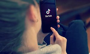 Kvinde holder smartphone med TikTok-logo