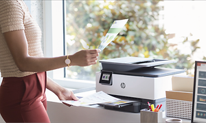 Kvinde holder op udskrift ved siden af en HP-printer