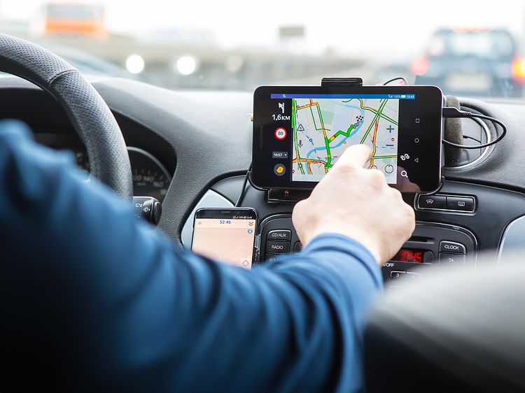 Mand der sidder i en bil og trykker på GPS-skærmen