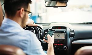 A mand der bruger sin mobil, imens han sidder stille i sin bil