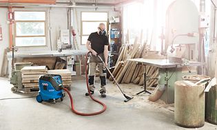 Man vacuuming workshop floor with Nilfisk Attix 44-2M IC