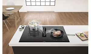 Bosch kogeplade med integreret emhætte, hvorpå der laves bøf og grøntsager
