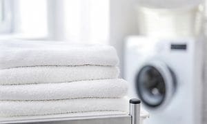Stabel med rene håndklæder foran en vaskemaskine