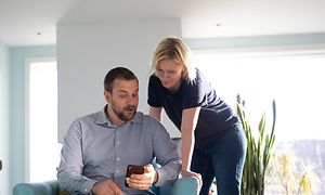 Mann og en kvinne som sjekker smarttelefonen deres
