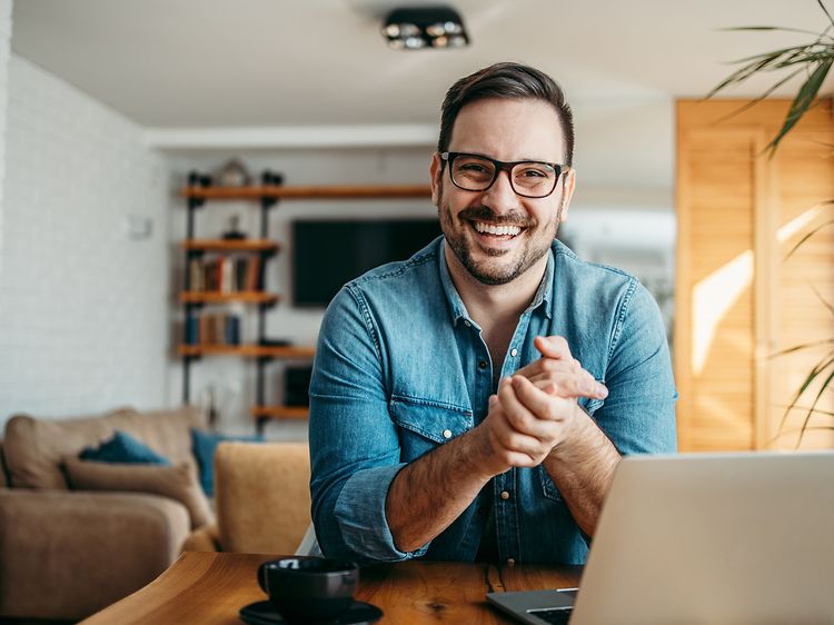 Smilende mand sidder ved sin bærbar computer