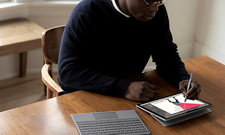 Mand sidder ved bord og bruger Microsoft Surface Pro 7 tablet