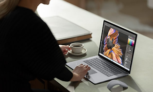 Kvinde drikker kaffe og redigerer billede på Microsoft Surface laptop